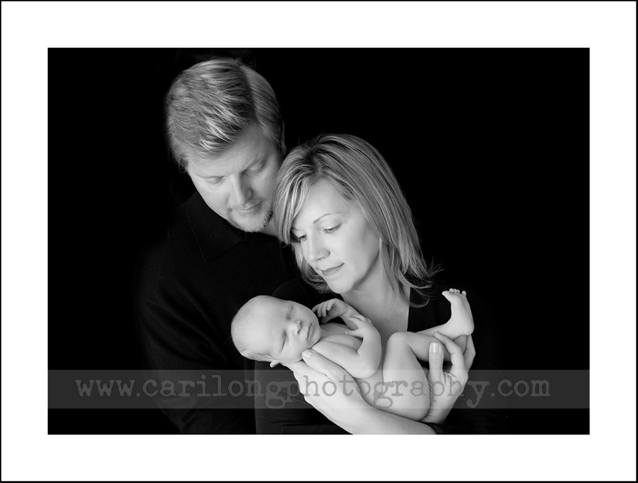 This image shows a beautiful newborn baby boy with his mom and dad. 
