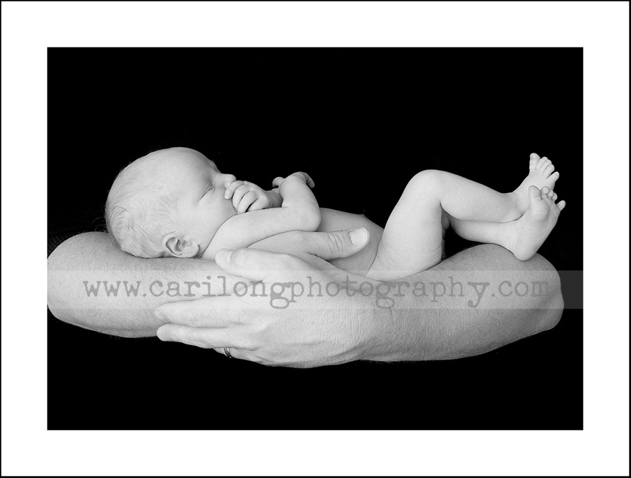 A newborn baby boy cradled in his dad's arms is photographed at our studio in Cary, NC.
