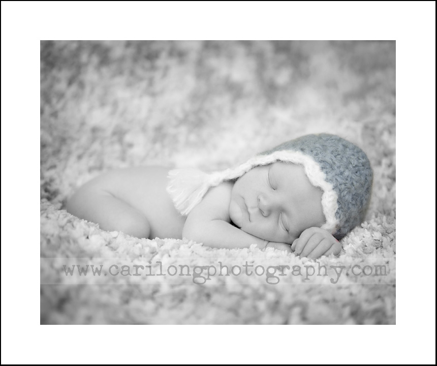 This image features a newborn baby boy in a blue pilot's hat. This session took place at our studio in downtown Cary.