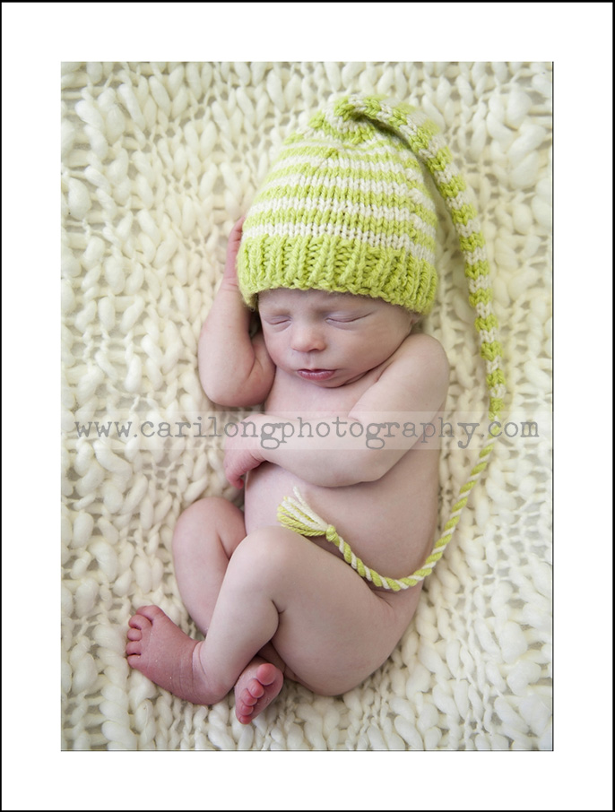 THis image shows a sweet little newborn baby boy photographed in raleigh, NC featuring a little elf hat.
